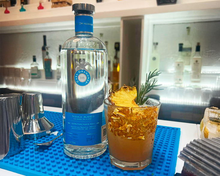 Degustación en bar elevado con caballitos de tequila alineados sobre la barra.